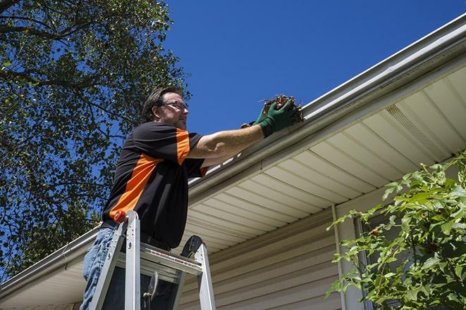 gutter repair specialist inspecting and fixing a damaged section in Canton